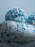 Cassava cat litter clumping into firm solid balls on a bed of white granules with blue flecks